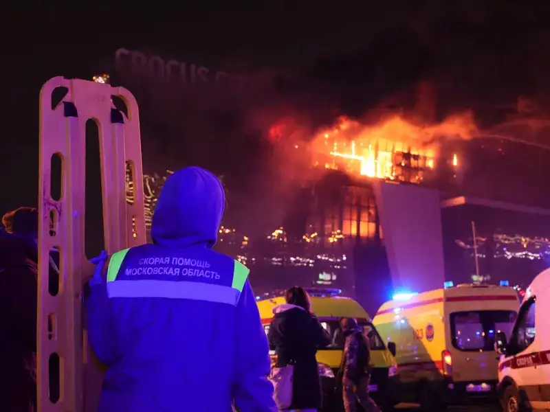 A medic stands near ambulances parked outside the burning building of the Crocus City Hall on the western edge of Moscow, Russia, Friday, March 22, 2024.